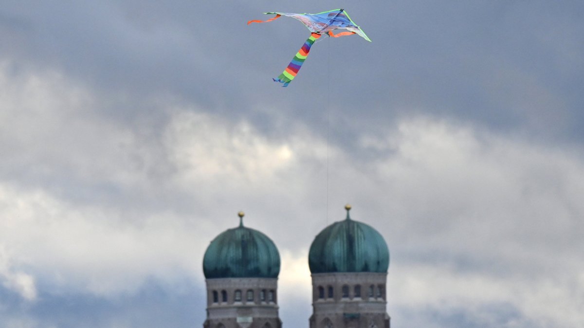Symbolbild: Ein Drachen in Regenbogenfarben über der Münchner Frauenkirche.