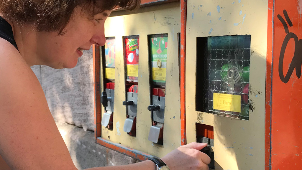 Eine Frau bedient einen Kaugummiautomaten