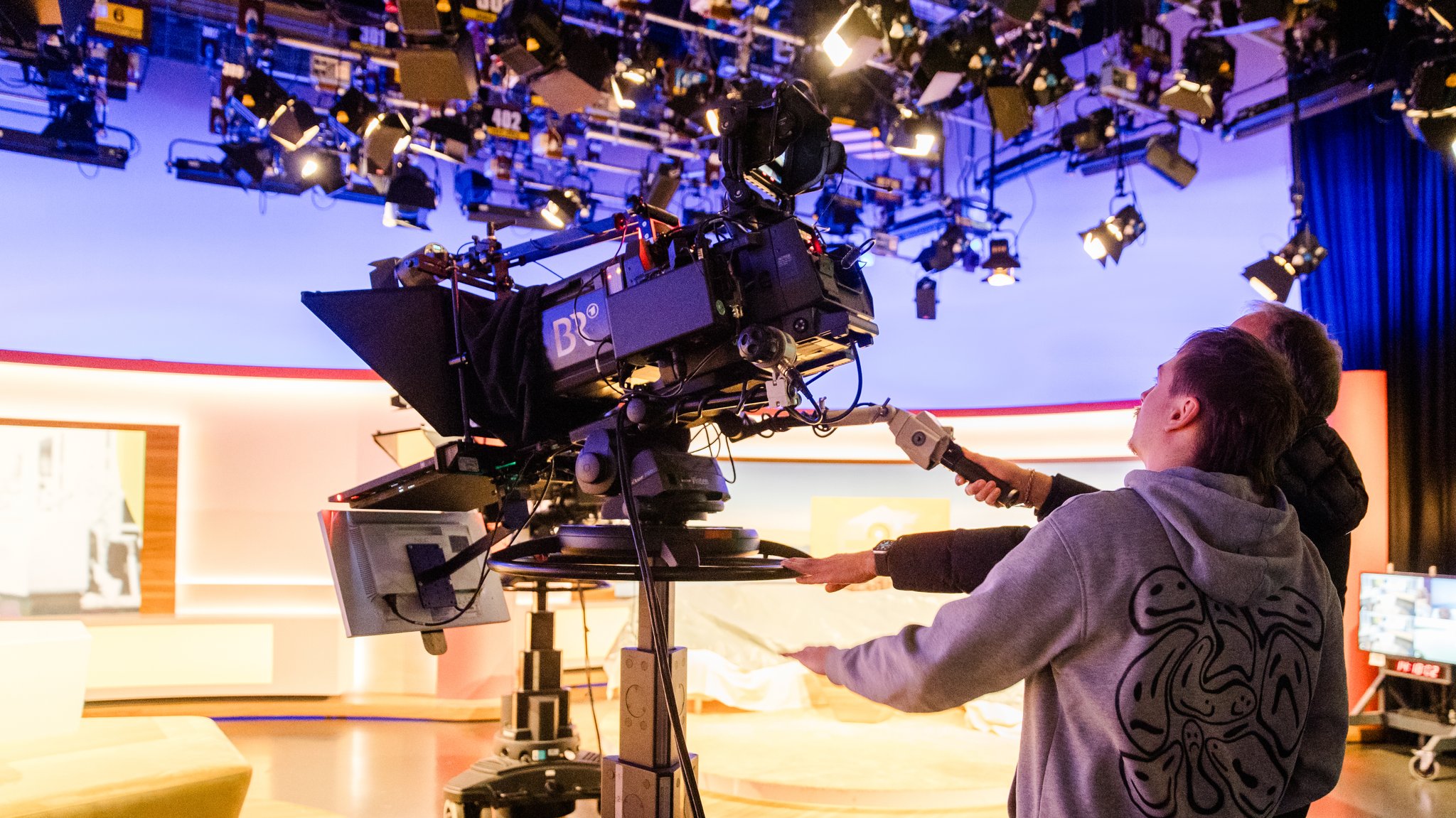 (Archivbild) Ein junger Mann wirft in einem BR-Fernsehstudio ein Blick hinter die Kamera 