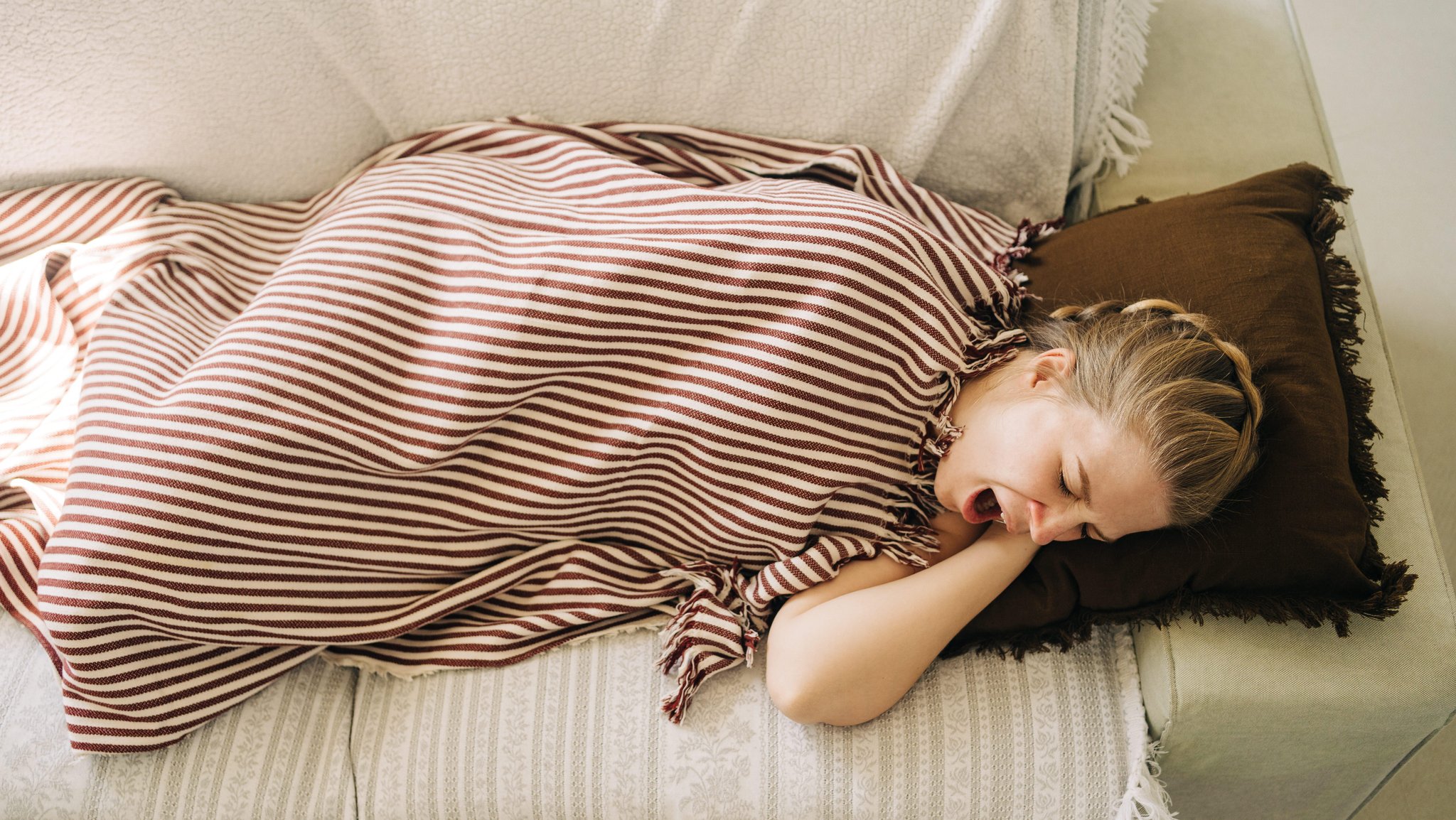 Frau macht einen Mittagsschlaf auf einem Sofa. | Bild: picture alliance / Shotshop | Addictive Stock Frau macht einen Mittagsschlaf auf einem Sofa.