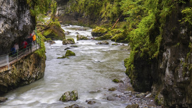 Ein Fluss fließt durch eine sich verengende Klamm. Besucher gehen neben dem Fluss auf einem Steg entlang. | Bild: picture alliance / imageBROKER | Wolfgang Veeser Ein Fluss fließt durch eine sich verengende Klamm. Besucher gehen neben dem Fluss auf einem Steg entlang.