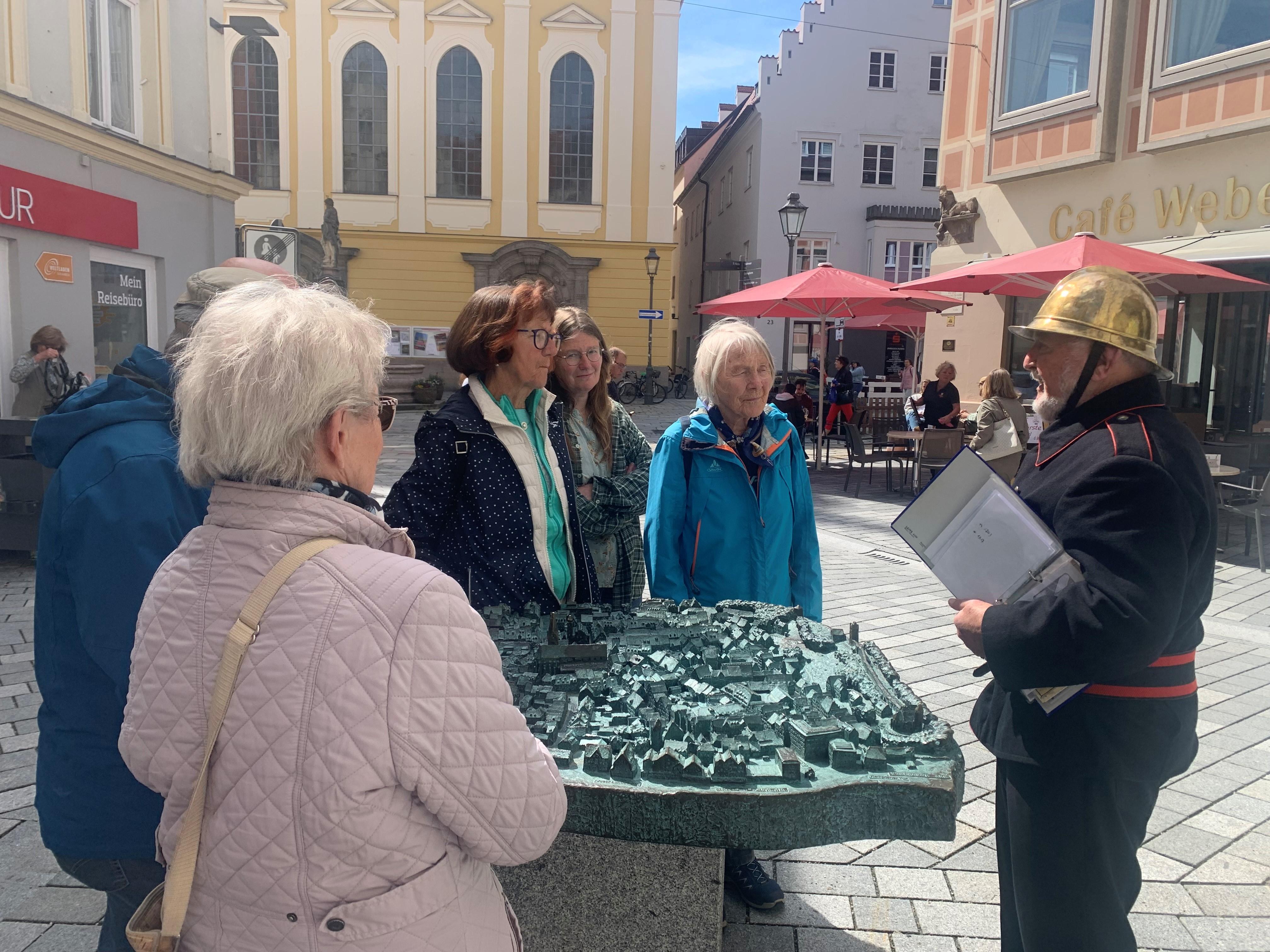 Mit goldenem Helm und schwarzem Hemd gekleidet zeigt der frühere Stadtbrandmeister Anton Heider Teilnehmern seiner Stadtführung das Kaufbeurer Stadtmodell.