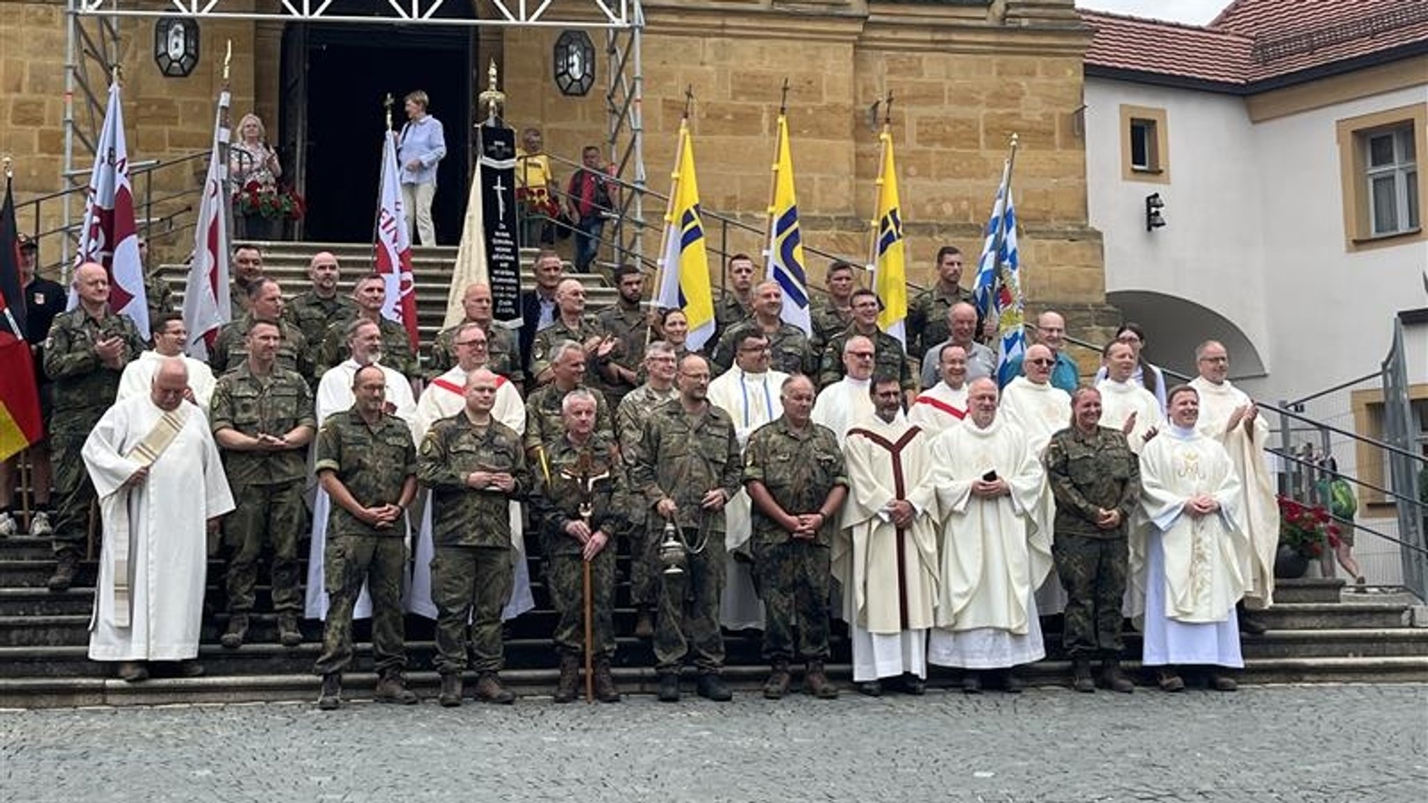 Die Soldaten und Geistlichen stehen vor einer Kirche.