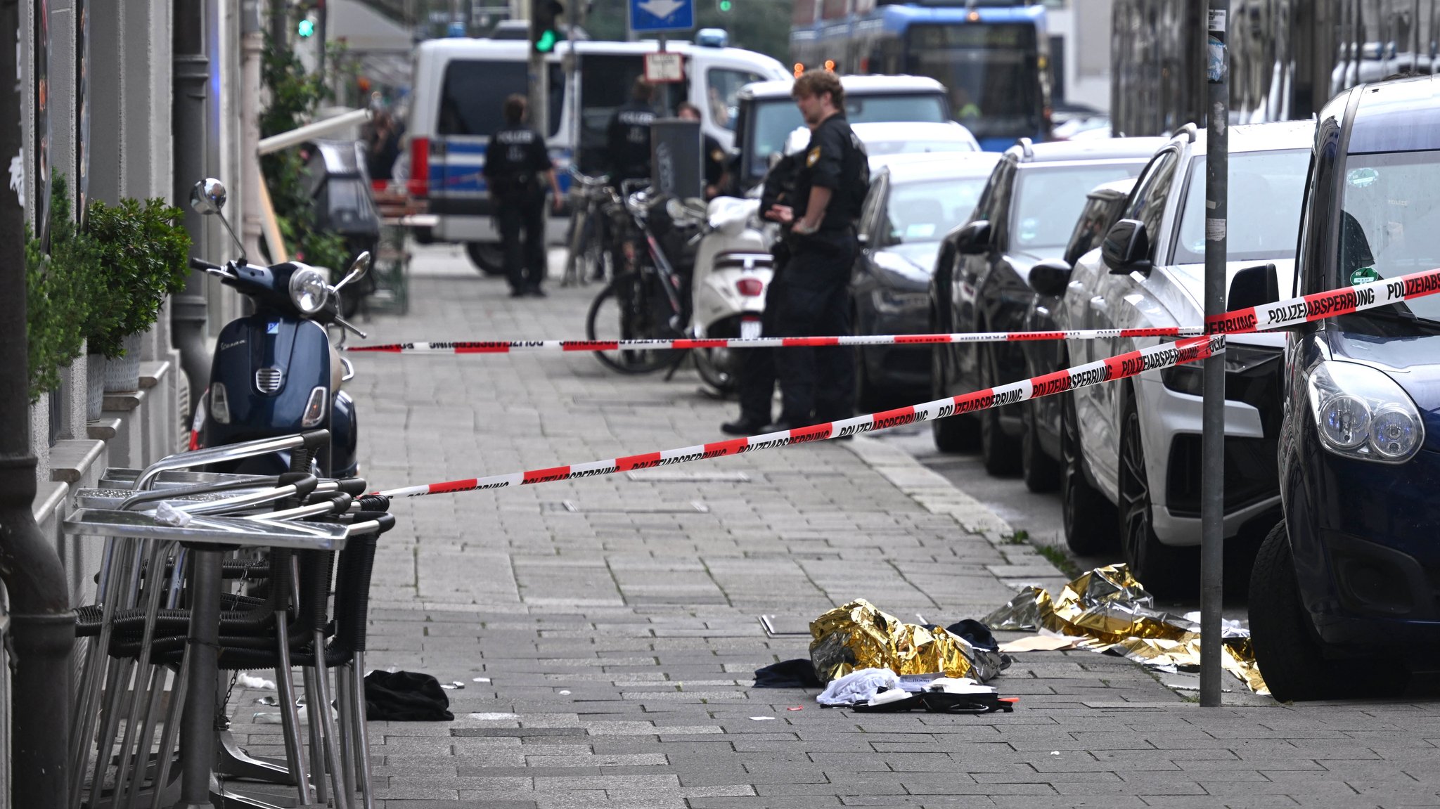 Rettungsdecken liegen neben Absperrband der Polizei auf einem Gehweg. 