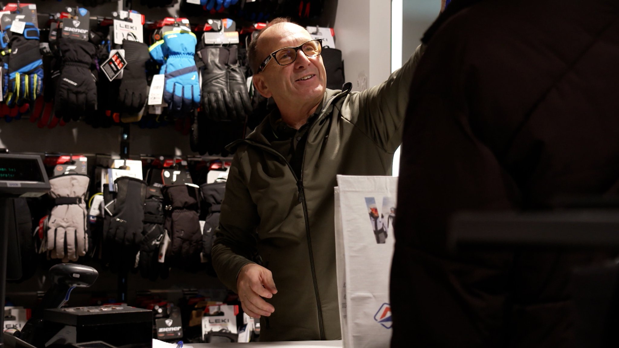 Ein Mann vor Handschuhen, die zum Verkauf an der Wand hängen. | Bild: BR Ein Mann vor Handschuhen, die zum Verkauf an der Wand hängen.