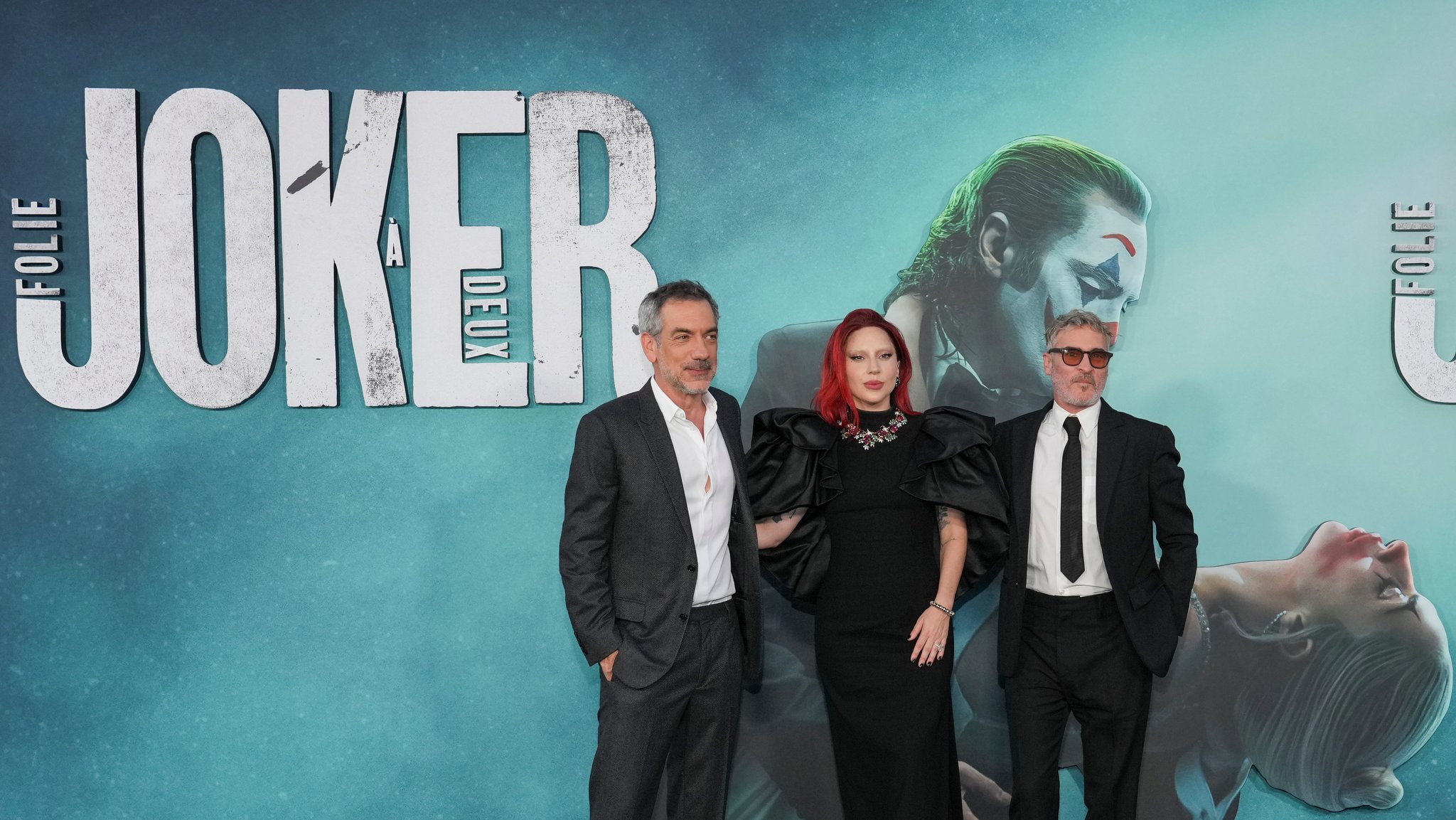 Todd Phillips, Lady Gaga, und Joaquin Phoenix stehen vor einem Plakat von "Joker: Folie a Deux" bei der Premiere des Films im TCL Chinese Theatre in Los Angeles. 