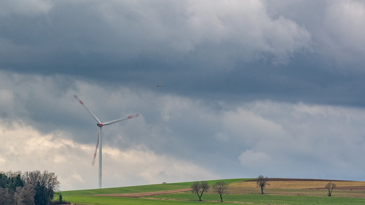 Eine Windkraftanlage bei Neunburg vorm Wald dreht sich vor dunklen Wolken.