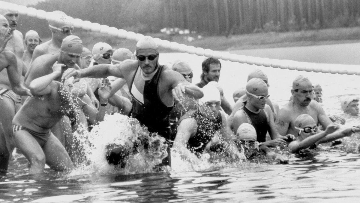 Bild in Schwarzweiß: Schwimmer im Wasser machen sich für den Triathlon 1984 bereit.