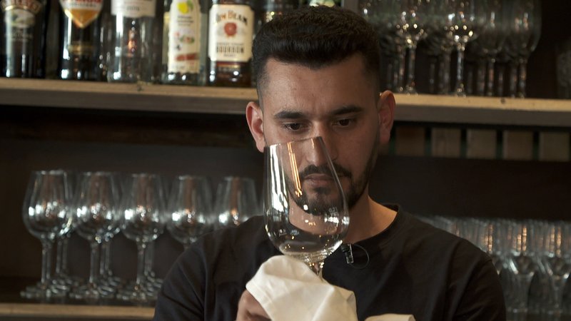 Achi beim Abtrocknen eines Weinglases | Bild: BR Achi beim Abtrocknen eines Weinglases