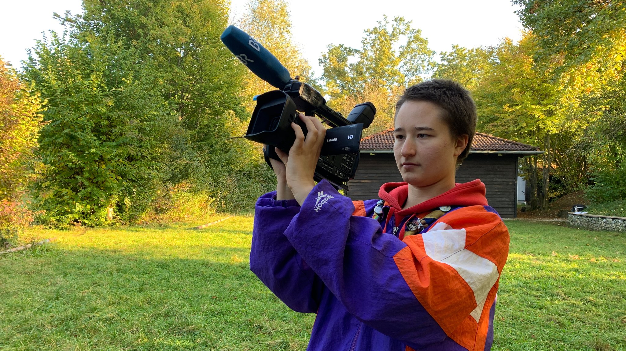 Eine junge Frau mit BR-VJ-Kamera in der Hand filmt in Richtung Himmel. 