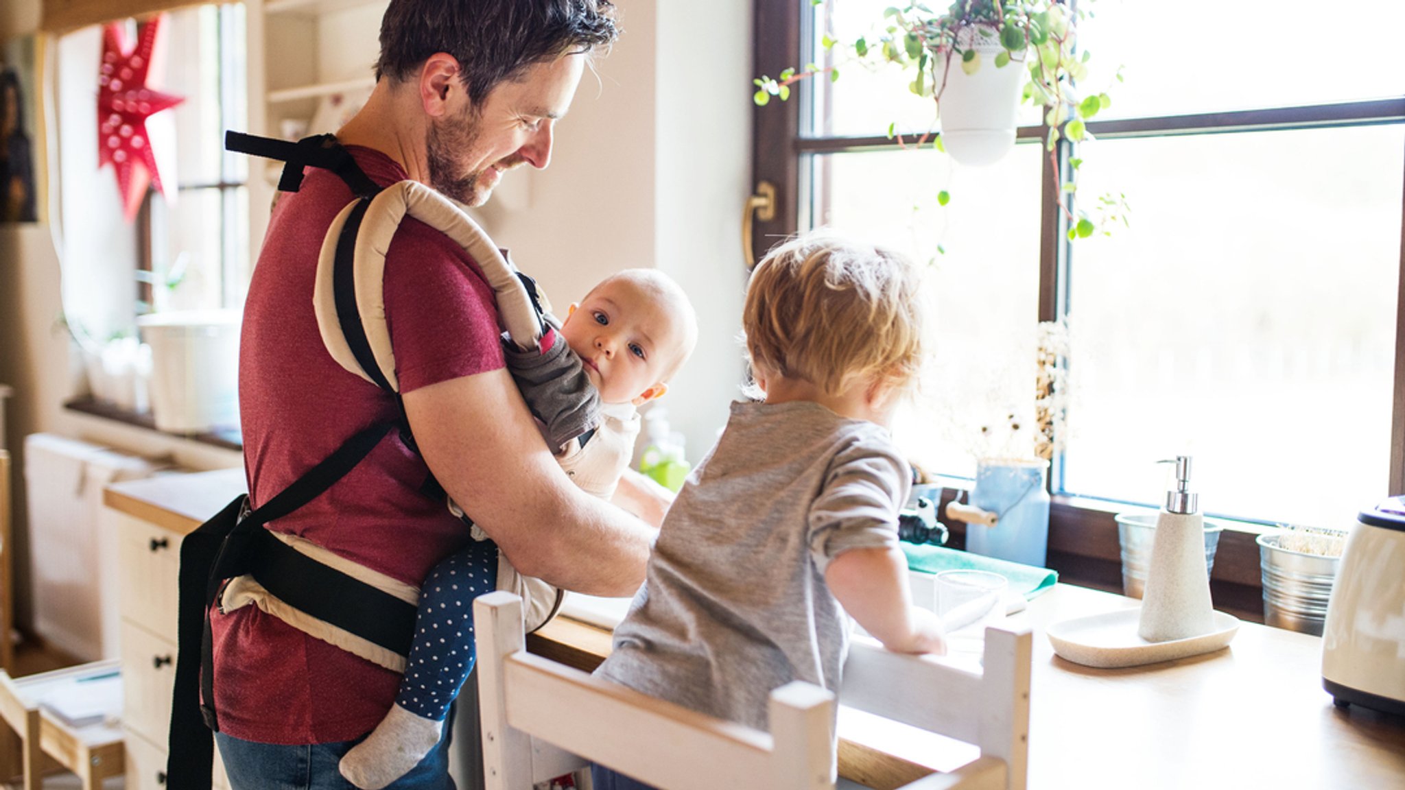 Ein Vater macht den Abwasch mit zwei kleinen Kindern.