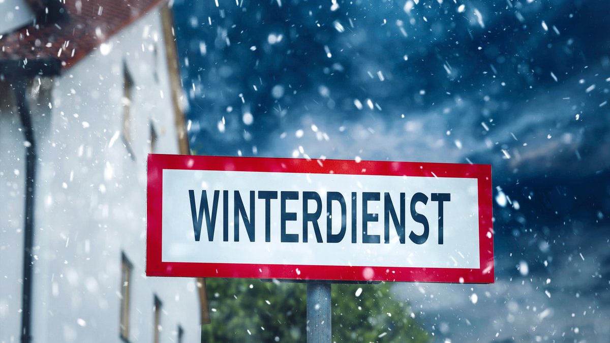 Schild mit der Aufschrift: Winterdienst vor einem Wohnhaus bei Schneefall im Winter