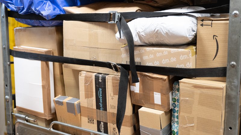 Pakete verschiedener Unternehmen in einem Wagen gestapelt. | Bild: picture alliance/dpa | Sebastian Kahnert Pakete verschiedener Unternehmen in einem Wagen gestapelt.