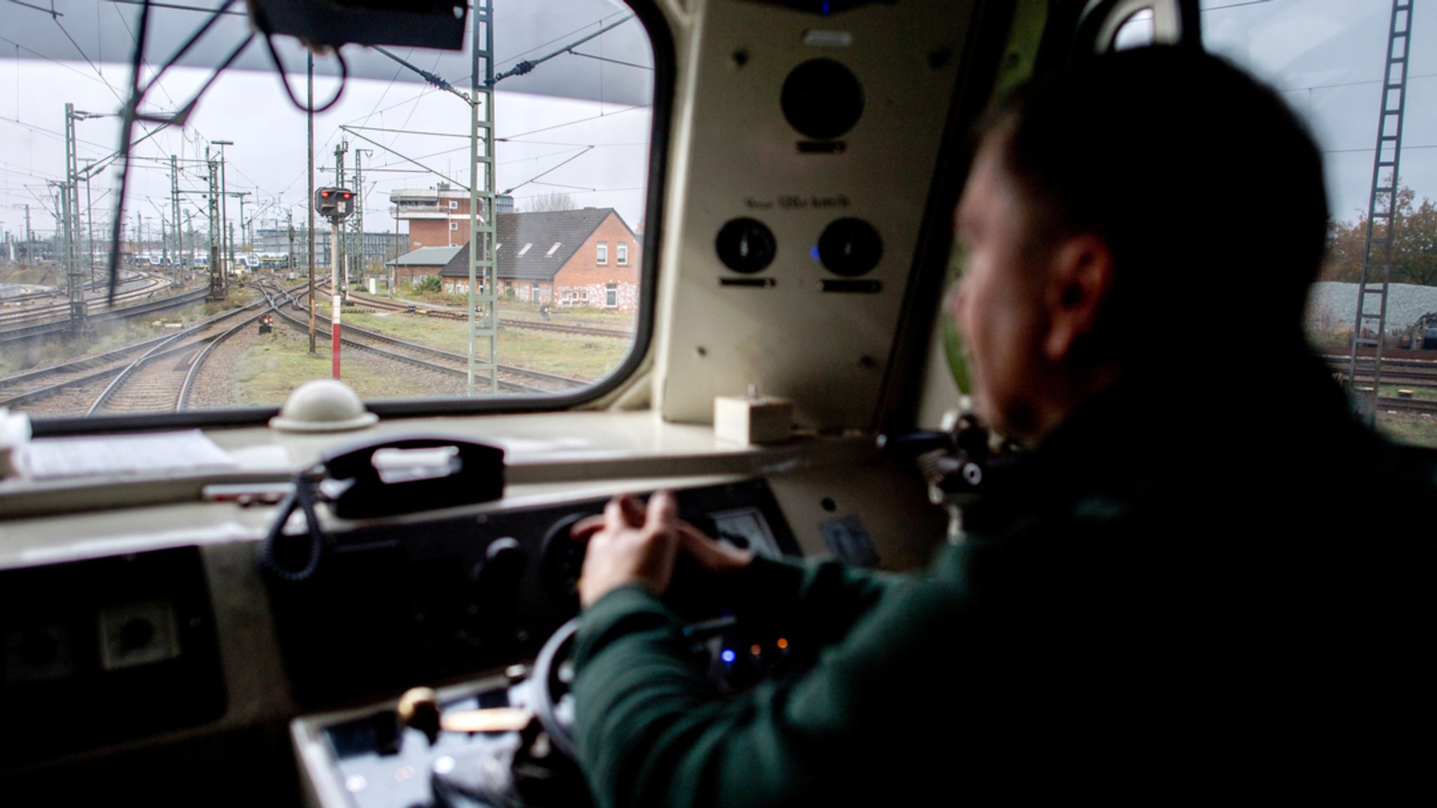 Ein Lokführer sitzt im Führerstand seiner Diesellokomotive und schaut auf die Gleise vor ihm