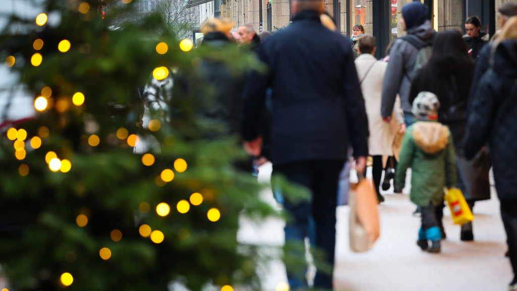 Passanten gehen durch eine weihnachtlich dekorierte Einkaufsstraße. (Symbolbild)