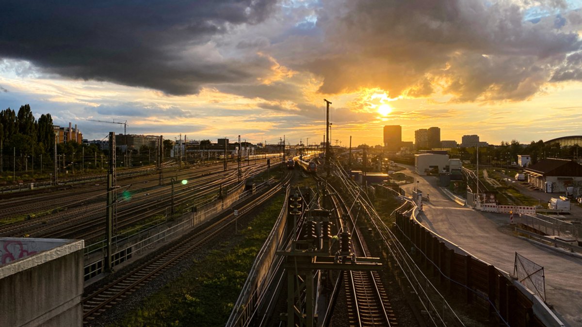 Sonnenuntergang, Bahnhofsgleise, im Hintergrund Hochhäuser in München 