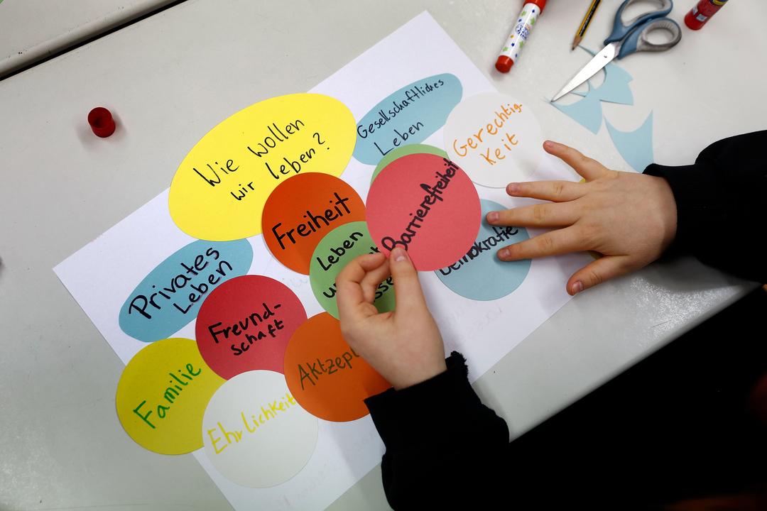 Auf einem Tisch eines Gymnasiums wird während eines Workshops von Schülerinnen und Schülern ein Plakat mit verschiedenen Begriffen wie "Barrierefreiheit" gestaltet zu ihren Vorstellungen für die Zukunft, und wie sie leben wollen.