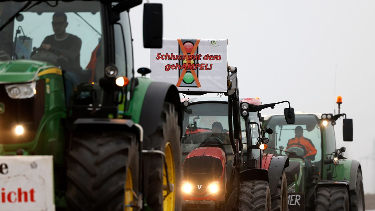 Teilnehmer der Bauernproteste fahren in Köln mit ihren Traktoren im Korso und präsentieren dabei Schilder mit Aufschriften, die Schluss mit ideologischer Politik und das Ende der Ampel fordern.