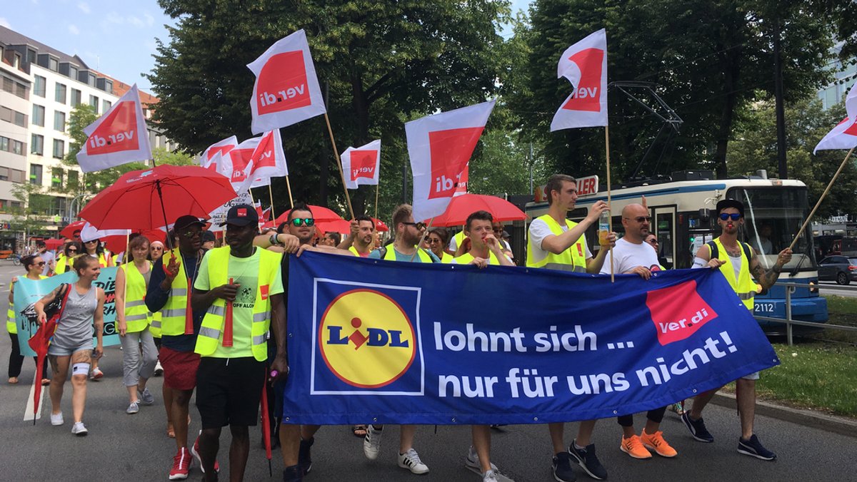 Streikende tragen Verdi-Flaggen sowie ein Banner mit der Aufschrift "Lidl lohnt sich... nur für uns nicht!"