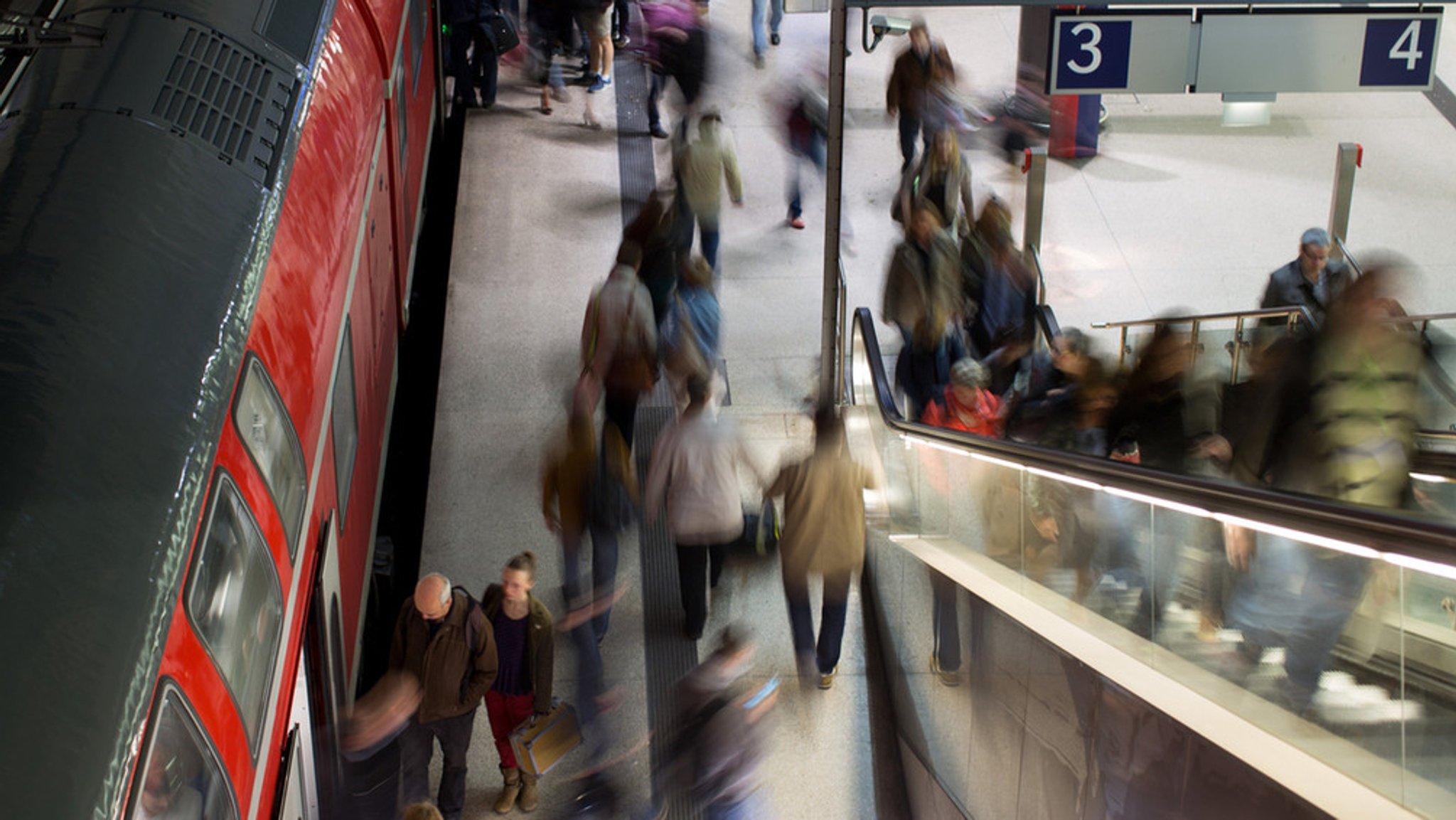 Zu sehen ist ein Bahnsteig und Menschen, die einen Zug verlassen oder einsteigen wollen