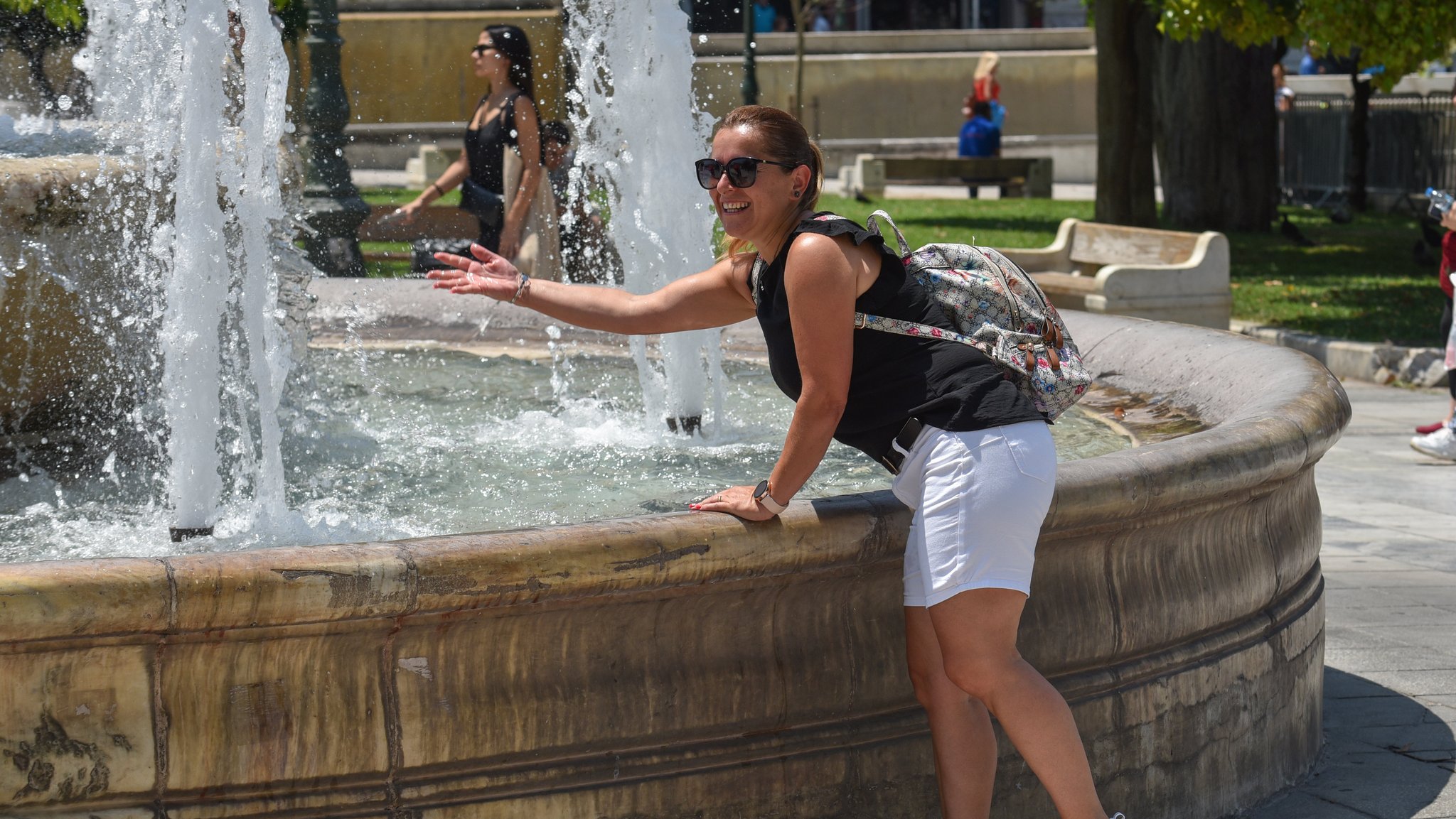 13.7.2023: Eine Frau kühlt sich an einem Brunnen in Athen ab. 