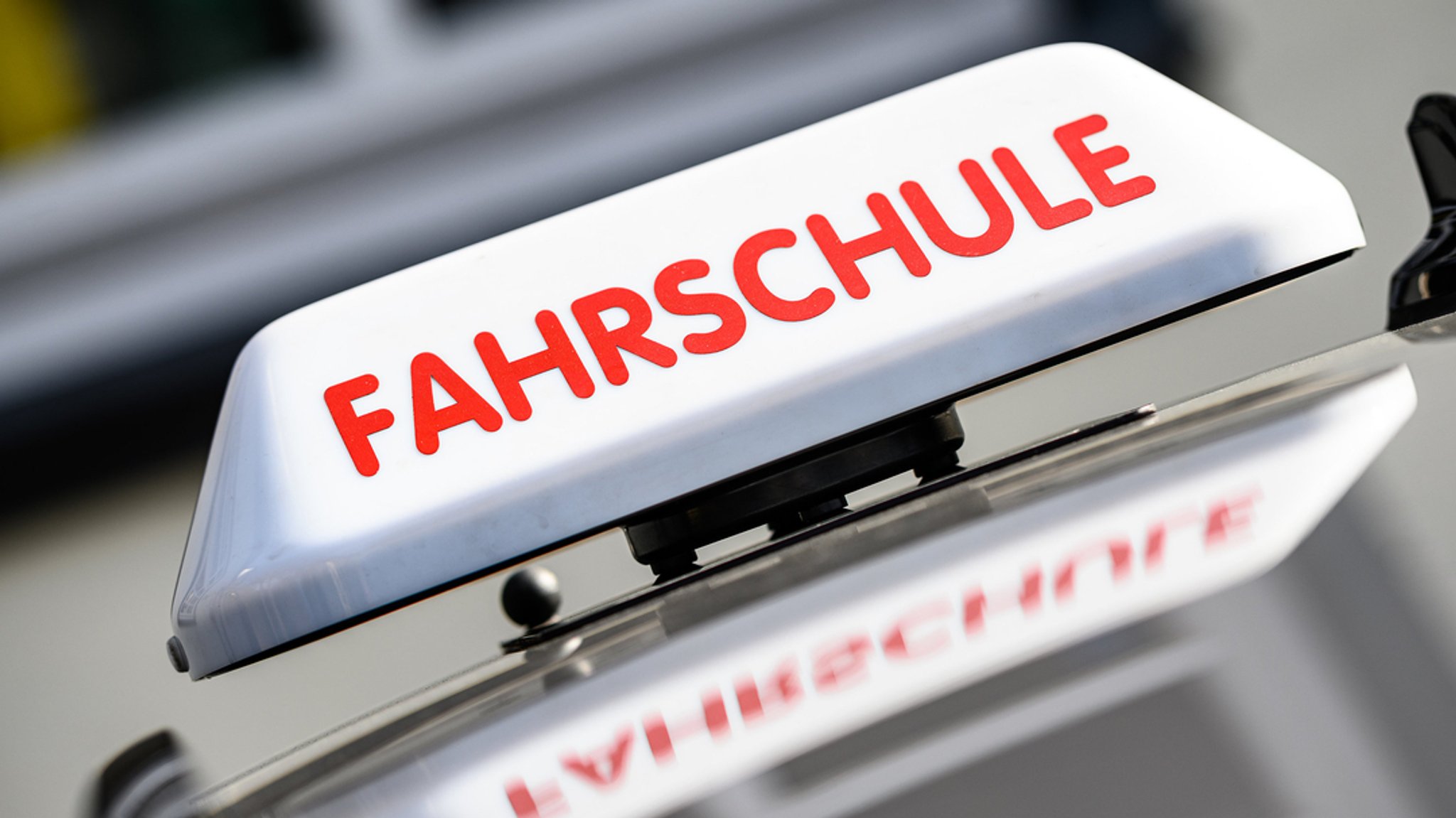 Nahaufnahme eines Autodachs, darauf ein Schild mit dem Hinweis: Fahrschule