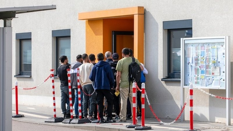 Neuankömmlinge warten auf die Registrierung an einem Eingang der Anker-Einrichtung Regensburg.