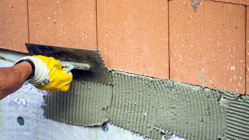 Ein Bauarbeiter verputzt eine Wand. 