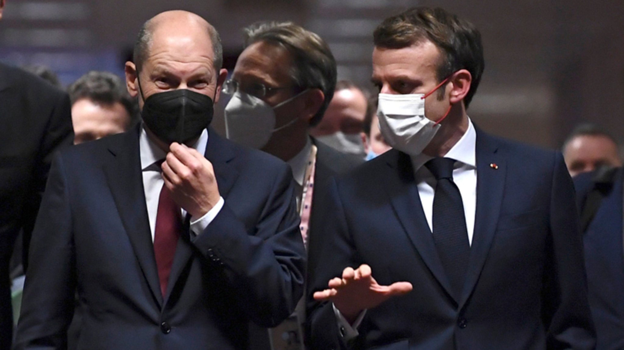 Olaf Scholz (M), Bundeskanzler, und Emmanuel Macron (r), Präsident von Frankreich, gehen vor einer abschließenden Pressekonferenz auf dem EU-Gipfel über einen Flur.