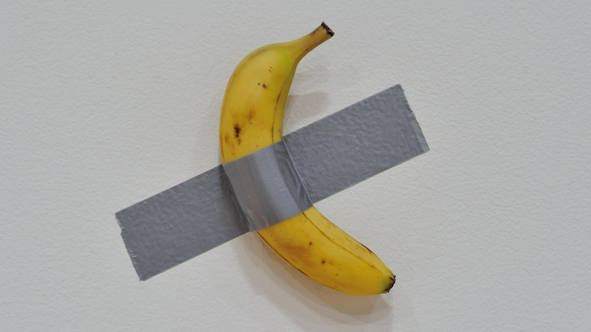 Eine Banane ist mit Klebeband an einer Wand festgeklebt.