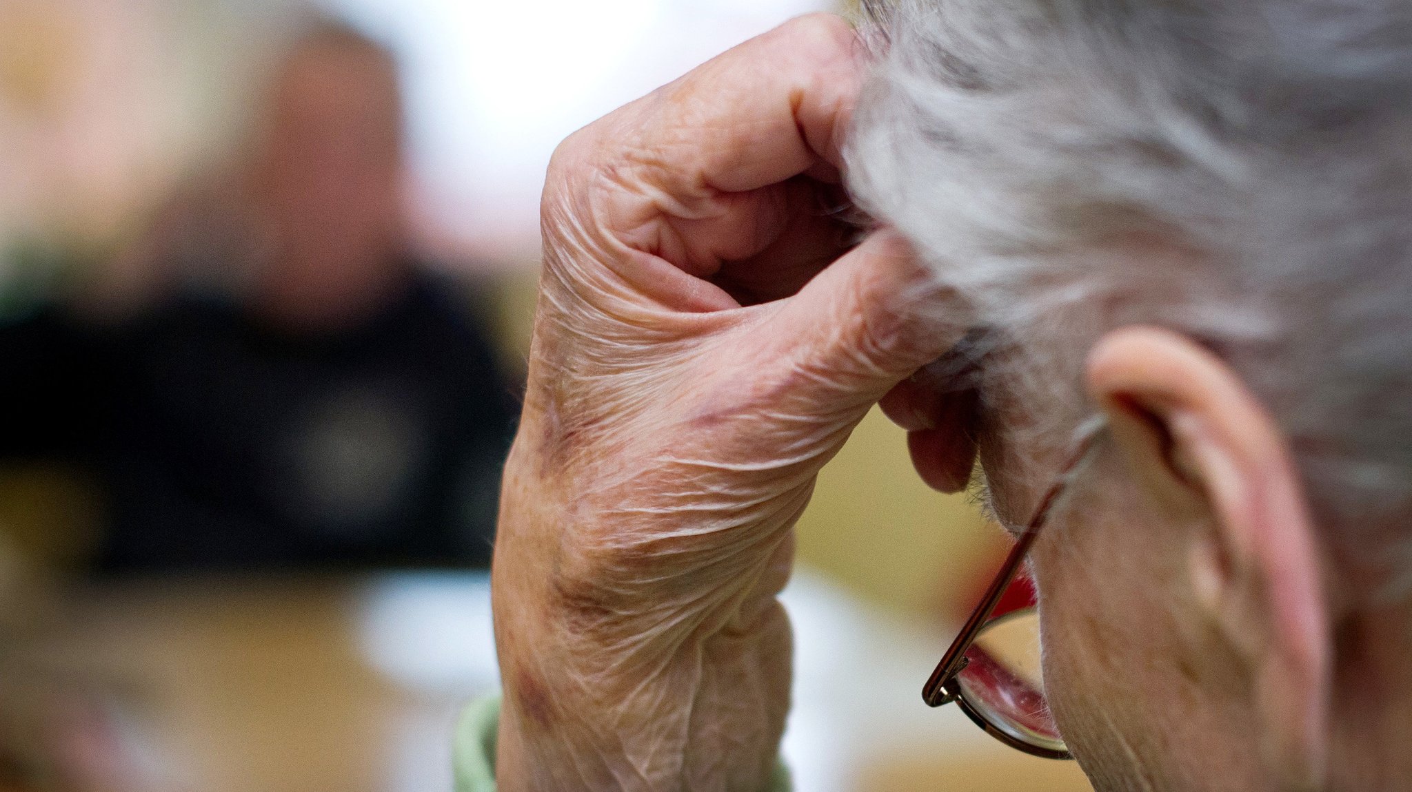 Eine alte und demenzkranke Frau sitzt in einem Pflegeheim.