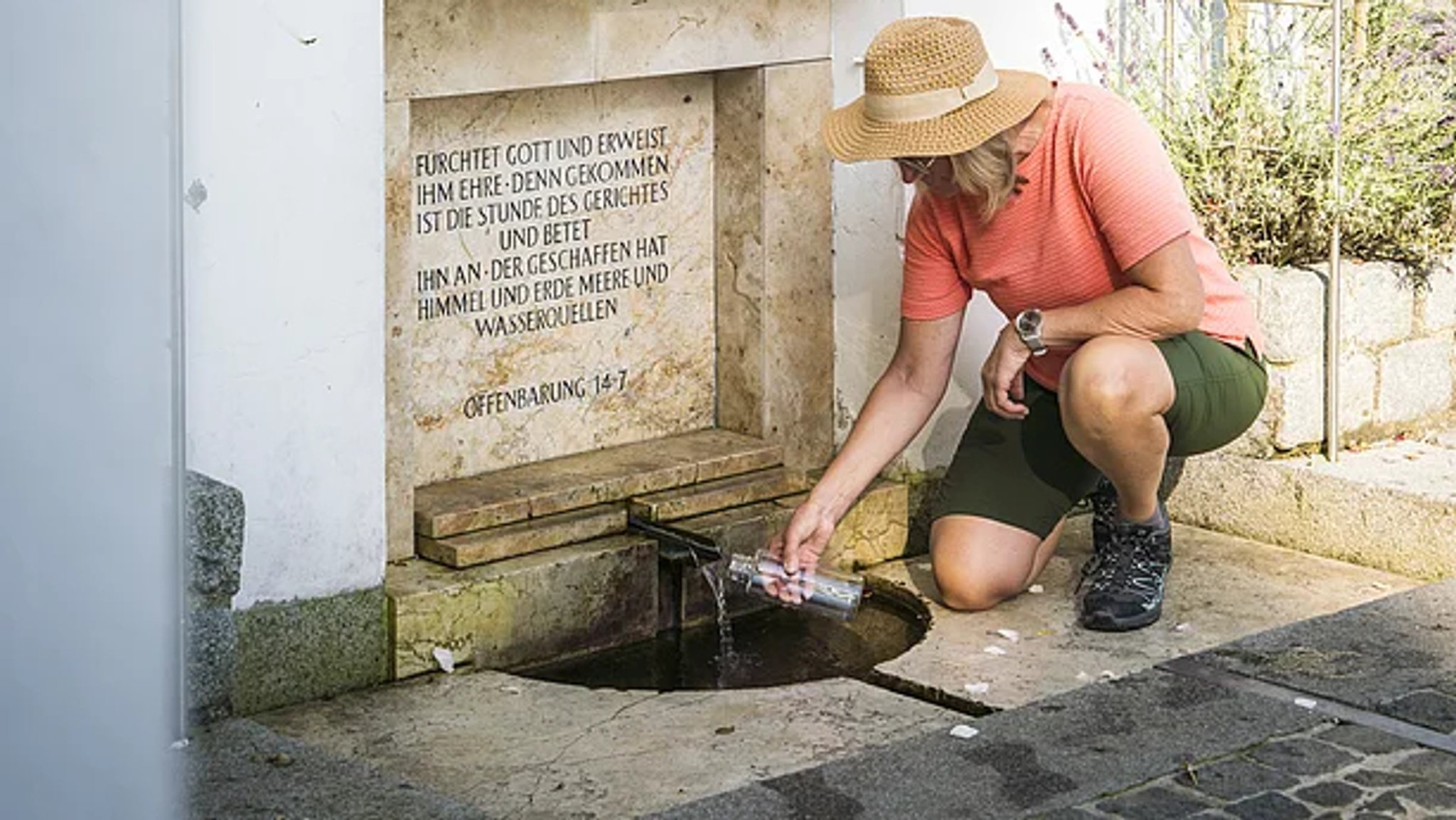 Eine Frau zapft Wasser aus der Heilquelle an der Wallfahrtskirche Frauenbründl bei Bad Abbach.