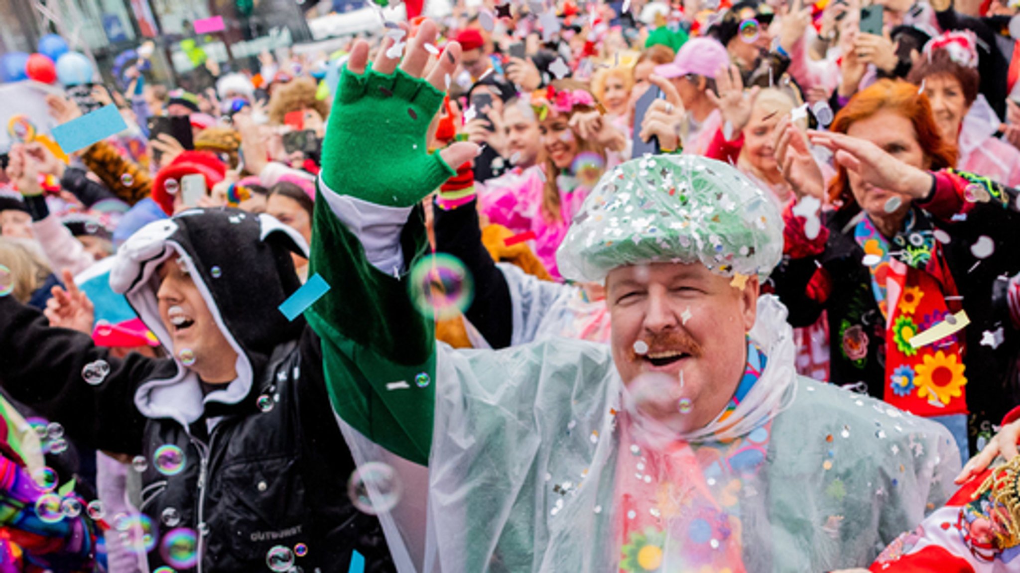 Fasching beginnt - kostümierte Menschen auf der Straße werfen Konfetti (Symbolbild)