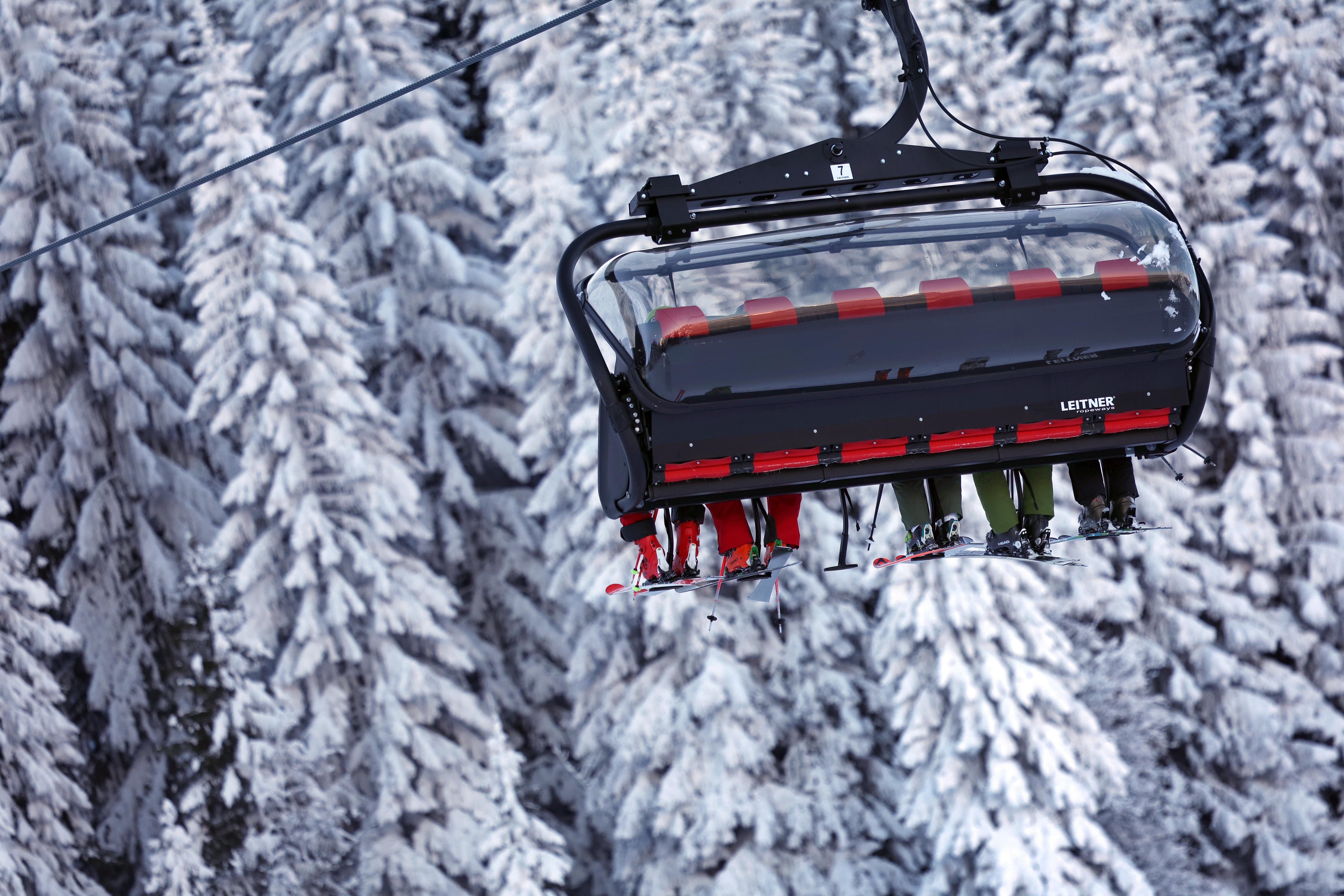 Skifahrer sitzen in einem Sessellift im Skigebiet Söllereck vor mit Schnee und Eis überzogenen Bäumen.