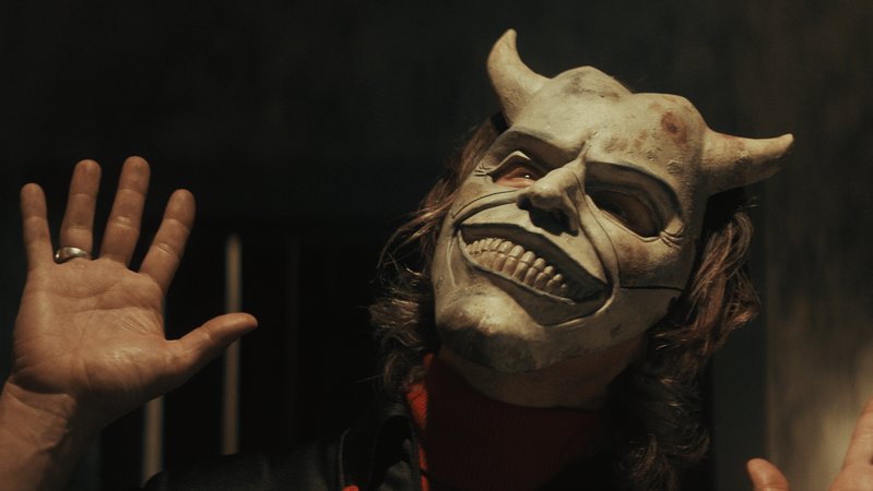 Ethan Hawke als Kindesentführer verbirgt sein teuflisches Grinsen lieber hinter einer Maske in "The Black Phone" (Filmszene).