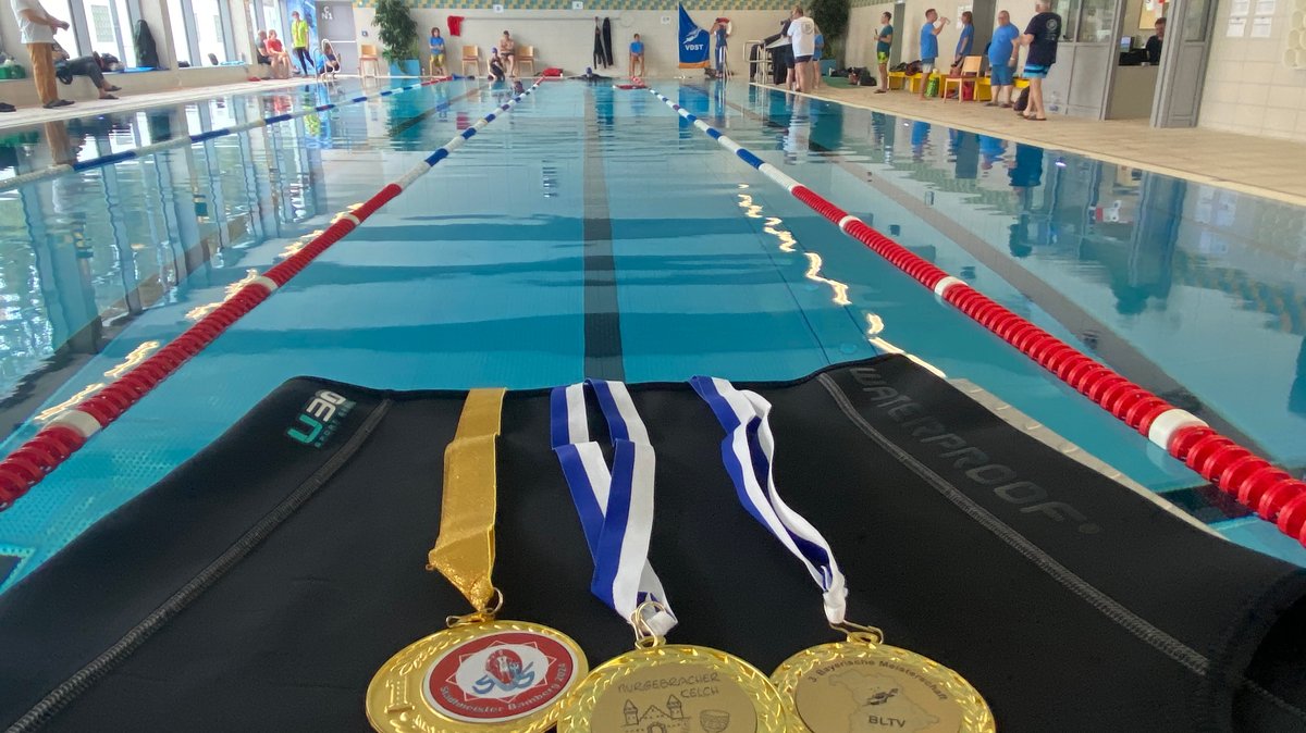 Medaillen liegen in an einem Schwimmbecken.