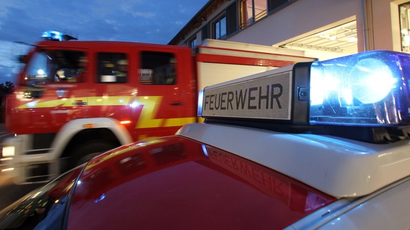 Zwei Feuerwehrautos fahren mit Blaulicht aus einer Halle. | Bild: picture-alliance/dpa Zwei Feuerwehrautos fahren mit Blaulicht aus einer Halle.