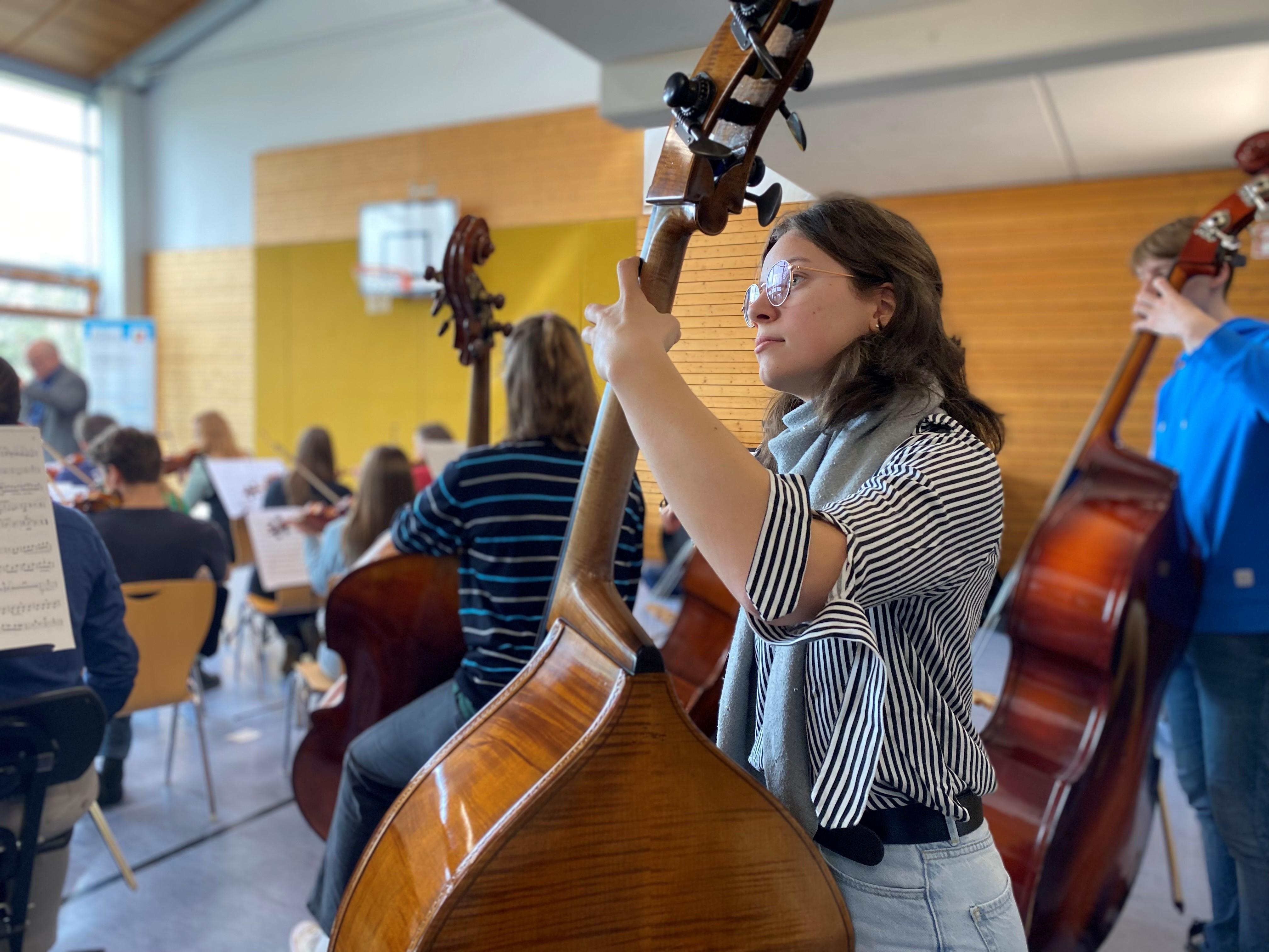 Eine Kontrabassistin beim Üben mit anderen in der Turnhalle des Schullandheims Pottenstein.