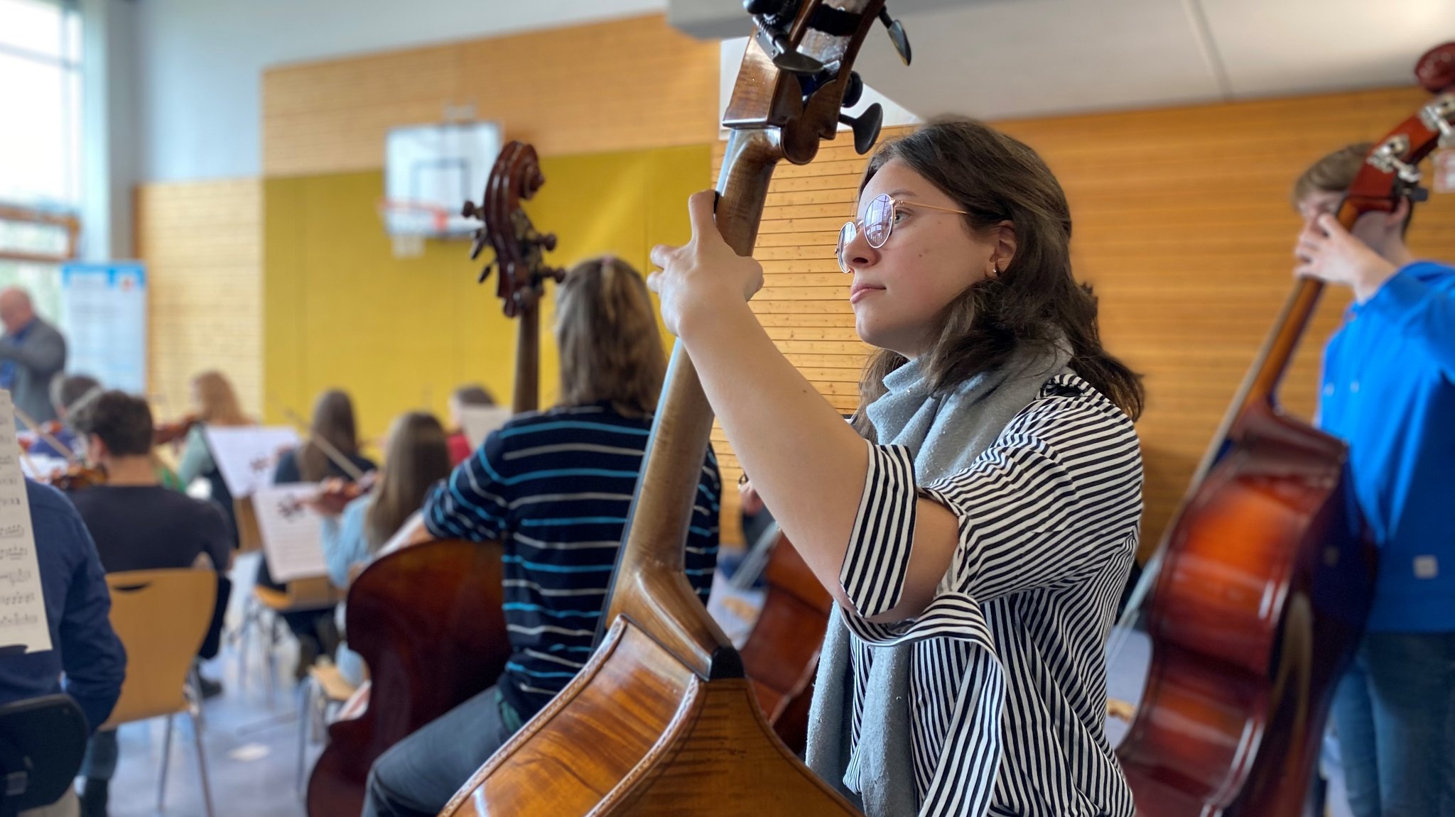 Eine Kontrabassistin beim Üben mit anderen in der Turnhalle des Schullandheims Pottenstein.