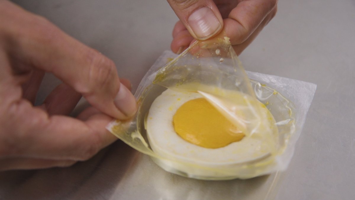 Ein veganes Ei, ein sogenanntes Egg-Patty, in einer Plastikfolie wird geöffnet