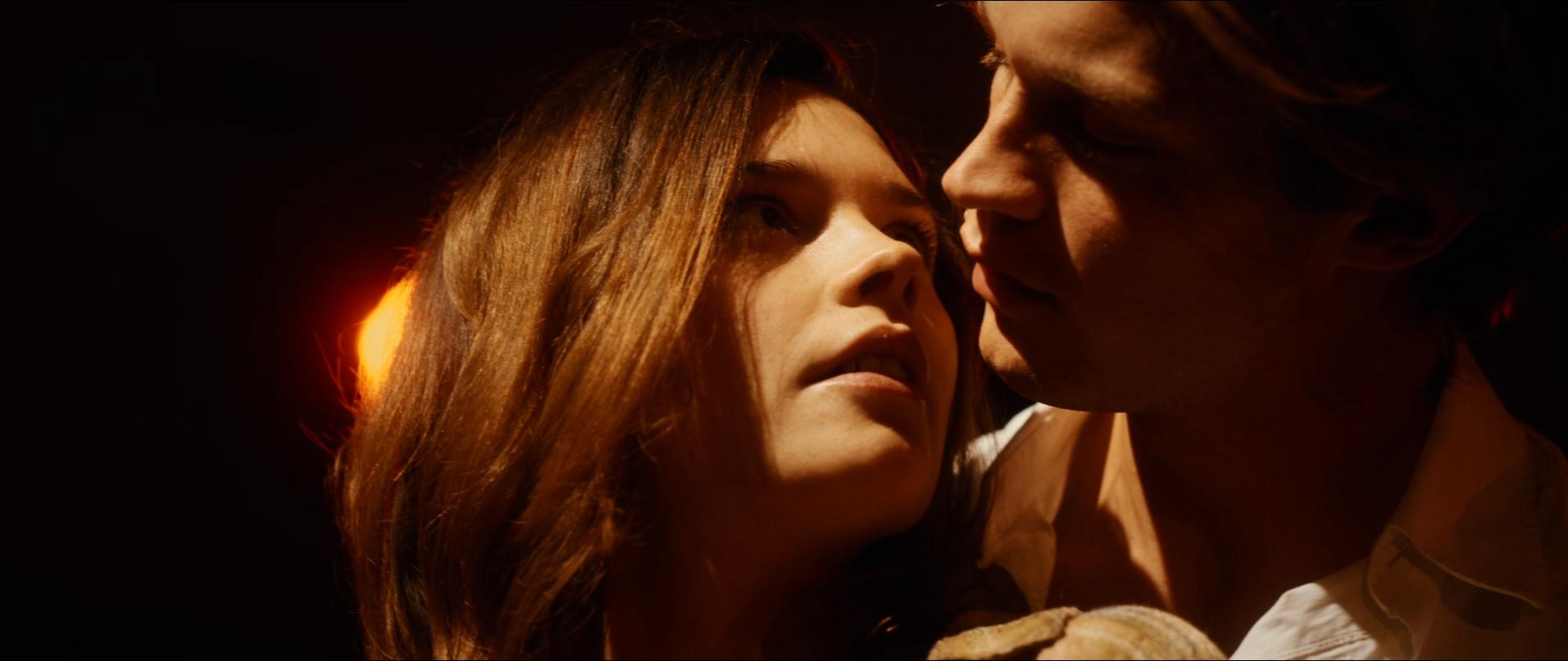 Eine junge Frau blickt sehnsüchtig auf einen über sie gebeugten Mann im Halbdunkel 