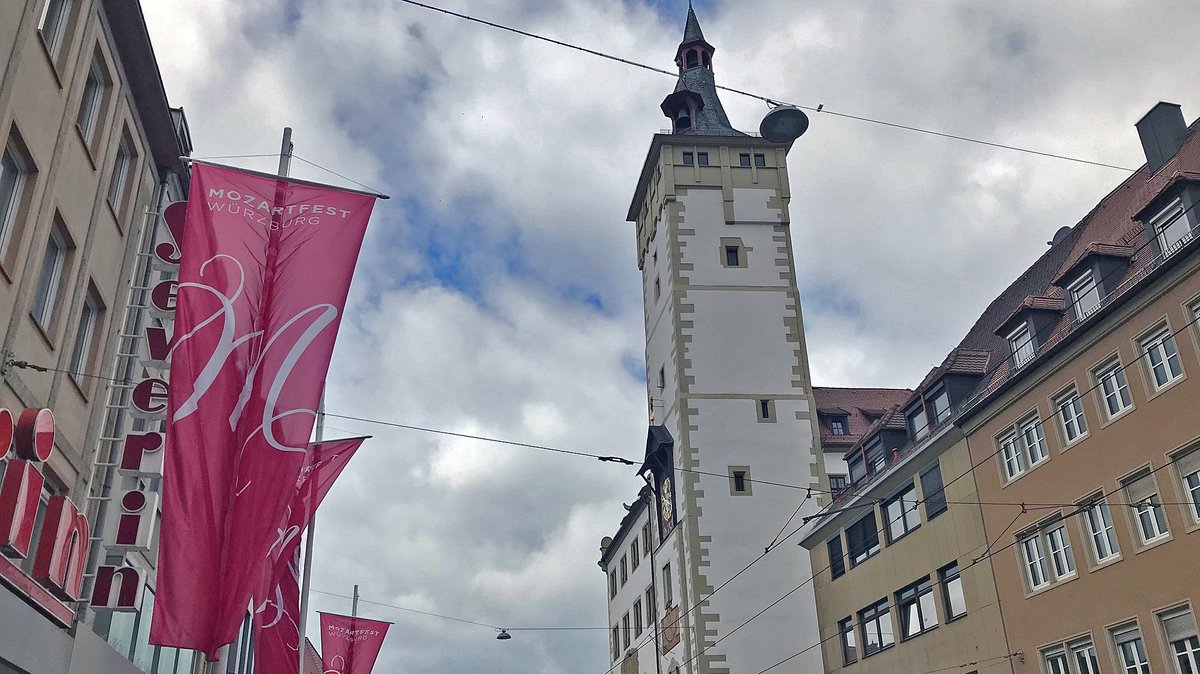 In der Domstraße in Würzburg: eine Mozartfest Flagge, daneben der Rathaus-Turm.