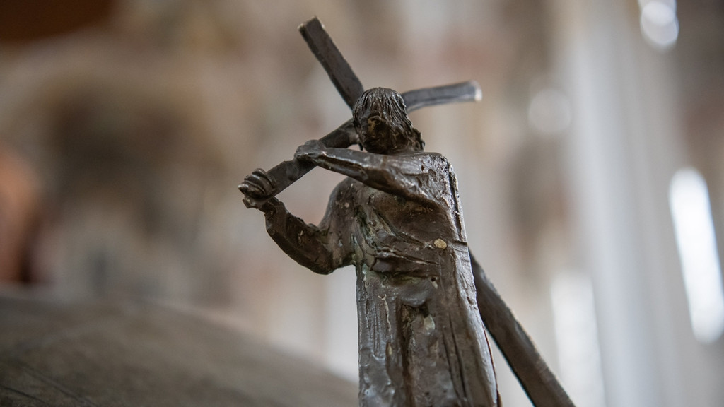 Bayern, München: Eine Bronzefigur, die Jesus zeigt, wie er das Kreuz trägt, steht in der Heilig Geist-Kirche am Taufbecken.