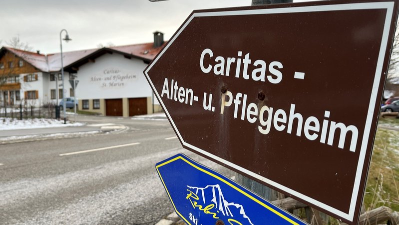 raunes Hinweisschild mit weißer Schrift auf das Caritas-Alten- und Pflegeheim in Seeg im Landkreis Ostallgäu