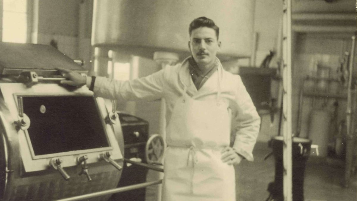 Schwarz-weiß Foto des jungen Michael Strauss vor einer Maschine in einer Fabrik des Unternehmnes.
