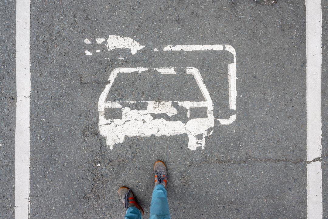 Ein abgeblättertes Piktogramm ist auf einem Parkplatz für Elektroautos zu sehen.