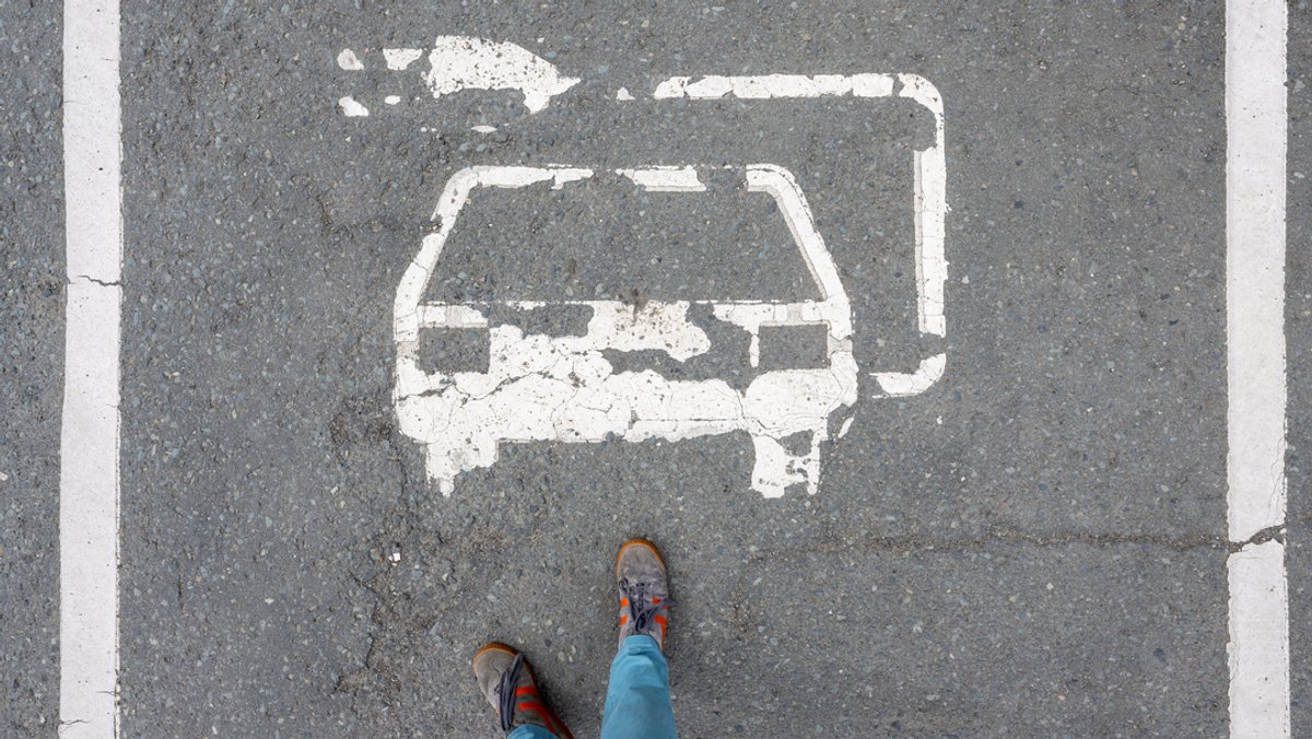 Ein abgeblättertes Piktogramm ist auf einem Parkplatz für Elektroautos zu sehen.