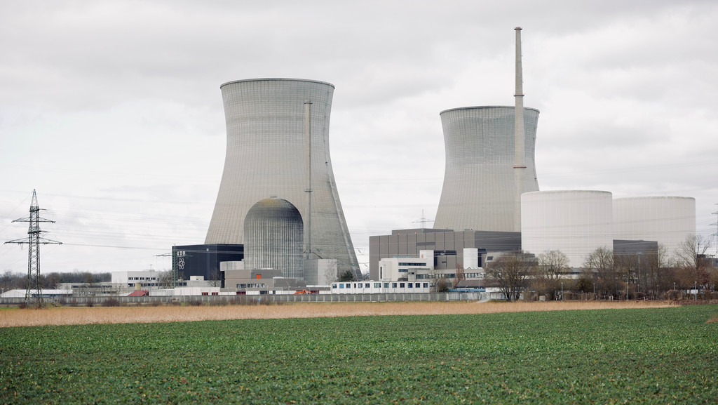 Bauten des AKW Gundremmingen mit den beiden Kühltürmen hinter einem grünen Feld