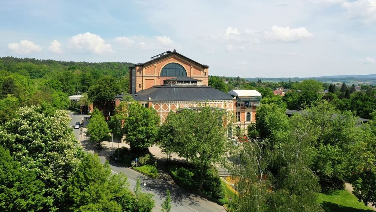 Drohnenaufnahme vom Bayreuther Festspielhaus, das von vielen Bäumen umgeben ist. 