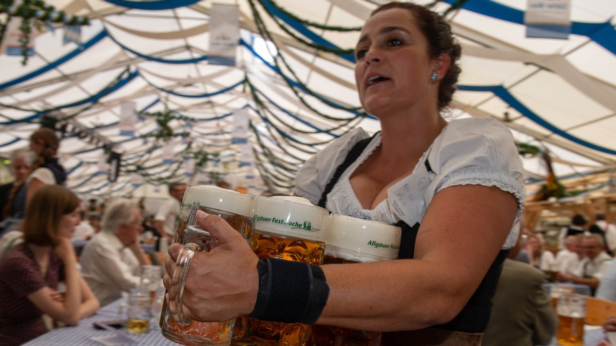 Eine Bedienung trägt im Festzelt der Allgäuer Festwoche mit Bier gefüllte Maßkrüge